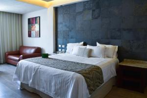 una camera d'albergo con un letto grande e una sedia di Hotel Portobelo a Guadalajara