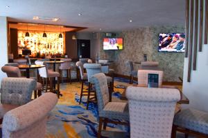 un bar con sillas, mesas y TV en Hotel Portobelo, en Guadalajara