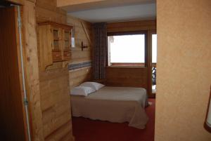 Habitación pequeña con cama y ventana en Hôtel De La Couronne, en Mijoux