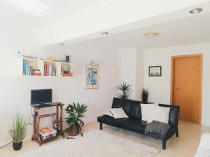 a black couch in a living room with plants at Quinta do Marinheiro - Meco in Aldeia do Meco