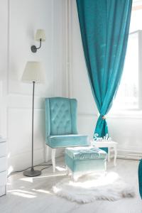 a blue chair in a white room with a window at Old Town Square Apartment Novi Sad in Novi Sad