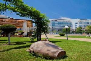 a large cow laying in the grass next to a tree at Yves 2 Bed apart at Sun Village Sunny Beach not far away from the sea in Sunny Beach