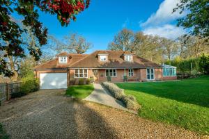 a large brick house with a white garage at Mews Hill, 5 bedroom New Forest Holiday Cottage in Fordingbridge