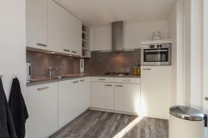 - une cuisine blanche avec des placards blancs et un évier dans l'établissement Vakantiewoning Zwinstraat Zoutelande, à Zoutelande