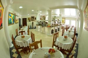 a restaurant with white tables and chairs and a kitchen at Itália Hotel in Telêmaco Borba