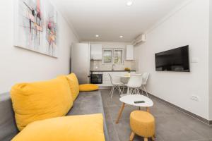 un soggiorno con divano giallo e tavolo di Apartments PETRUSIC a Makarska
