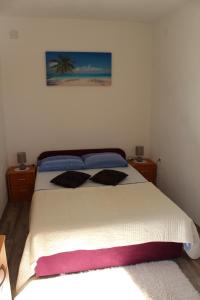 a bedroom with a bed with two pillows on it at Apartments Grmaca in Trogir