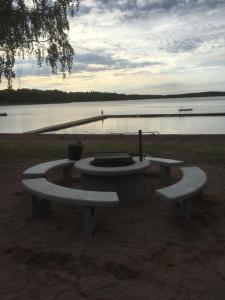 a picnic table with two benches next to a body of water at Odensvi Vandrarhem in Odensvi