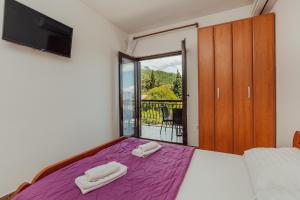 a bedroom with a purple bed with a balcony at Apartments Bonaca in Igalo
