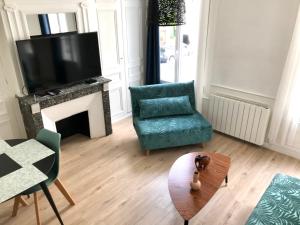 a living room with a green chair and a television at La Savane du Donjon in Rouen