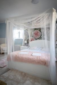 a bedroom with a white canopy bed with roses at Gyula Panzio in Gyula