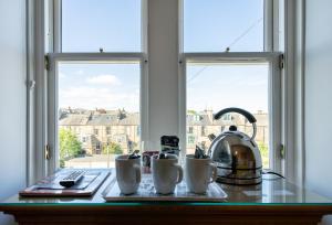 a table with mugs and a tea kettle on a window at Kingsley Guest House in Edinburgh