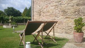 a pair of chairs sitting next to a stone wall at Torres de Moreda in A Estrada