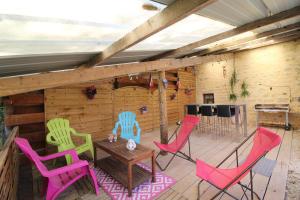 a patio with colorful chairs and a table on a deck at La ferme aux chats in Formigny