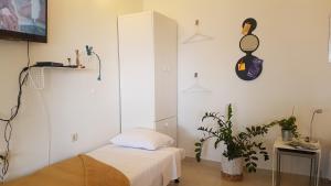 ein weißes Zimmer mit einem Bett und einer Pflanze in der Unterkunft Studio apartman Terrace-Sevid in Sevid