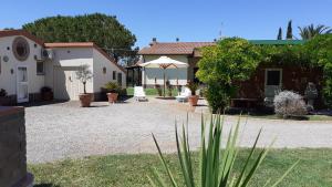 einen Innenhof mit einem Haus und einem Sonnenschirm in der Unterkunft Agriturismo Prato Verde in Principina a Mare