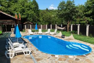 a swimming pool with chairs and umbrellas at Карамановите къщи in Apriltsi
