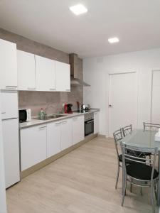 eine Küche mit weißen Schränken und einem Tisch mit Stühlen in der Unterkunft Apartamento Torre de Hércules in A Coruña