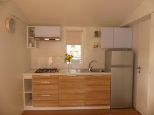 a kitchen with wooden cabinets and a white refrigerator at Blue Wave Mobile Home in Biograd na Moru
