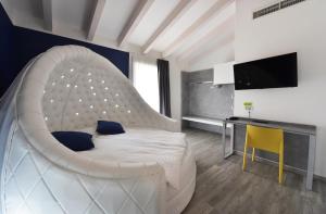 1 dormitorio con 1 cama blanca grande y escritorio en Primavera ApartmentSuites en Riva del Garda