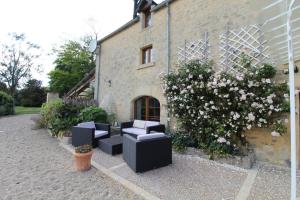 a patio with black chairs and flowers next to a building at La ferme aux chats in Formigny