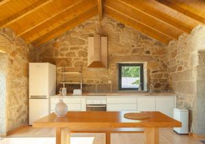 a kitchen with a wooden table in a stone building at Casas d'Oliva in Caramulo