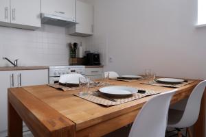 a kitchen with a wooden table with plates and glasses at Clermont Centre- Appartement Privé in Clermont