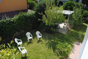 a group of white chairs sitting in the grass at Summer Beach Rooms in Fontane Bianche