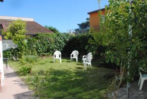 two white chairs sitting in the grass in a garden at Summer Beach Rooms in Fontane Bianche