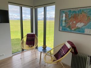 2 sillas y una mesa en una habitación con ventanas en Brú Guesthouse, en Hvolsvöllur