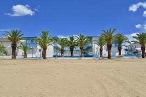 una fila de palmeras en una playa con un edificio en Olympion Beach Hotel, en Gerakini