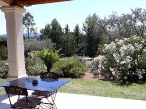 une table bleue et des chaises sur une terrasse couverte avec un jardin dans l'établissement Parfums de Provence "Le Lavandin" Piscine chauffée & Spa, à Vaison-la-Romaine