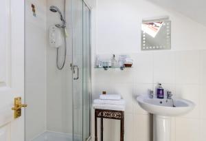 a white bathroom with a shower and a sink at Wynnstay House in Harrogate