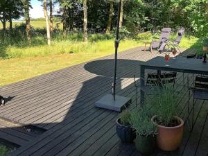 eine Holzterrasse mit einem Sonnenschirm, einem Tisch und Stühlen in der Unterkunft 6 person holiday home in Nyk bing M in Hesselbjerg
