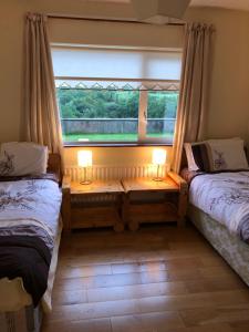 two beds in a room with a window and two lamps at Drumcoura Bungalow in Leitrim