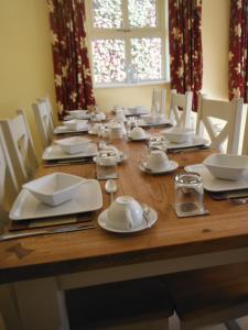 a wooden table with white plates and dishes on it at Inspiration Lodge in Anascaul