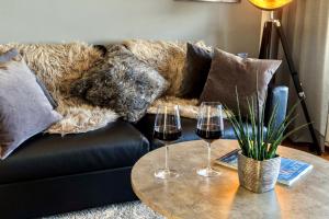 a couch with two glasses of wine on a table at Auszeit Apartment LAKESIDE mit Privatstrand in Friedrichshafen