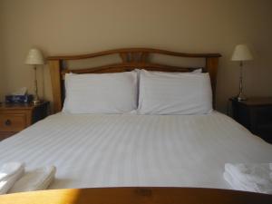 a bedroom with a bed with white sheets and pillows at Inspiration Lodge in Anascaul