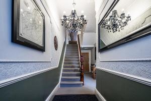 einen Flur mit einer Treppe und einem Kronleuchter in der Unterkunft Fountains Guest House - Harrogate Stays in Harrogate