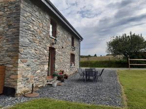 une maison en pierre avec une table et des chaises à l'extérieur dans l'établissement gîte Le cheval ardennais, à Gouvy