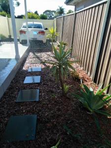 a garden with a car parked next to a fence at Ashley's Retreat Umina Beach in Umina