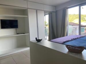 Schlafzimmer mit einem Bett, einem TV und einem Balkon in der Unterkunft Flat Camorim em Angra dos Reis/RJ. in Angra dos Reis