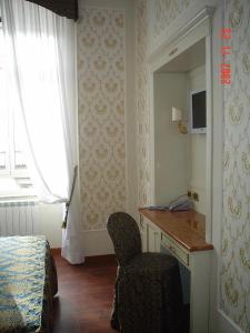 una camera da letto con scrivania, sedia e specchio di Hotel Dina a Roma