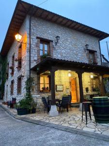 una casa de piedra con una mesa y sillas delante de ella en La Casona del Jou en Ortiguero