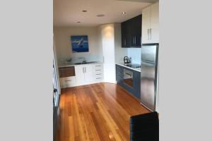 a kitchen with white cabinets and a wooden floor at Amazing Ansons Bay Absolute Waterfront Beach House in Ansons Bay