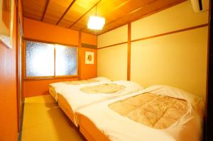 two beds in a room with two windows at Momiji Takayama in Takayama