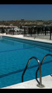 a large blue swimming pool with a metal fence at Sunset Beach in Costa da Caparica