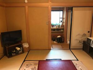 uma sala de estar com uma televisão de ecrã plano e uma sala de estar em 小京都の宿 へうたん em Nishio