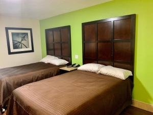 モンゴメリーにあるSunrise Extended Stay Hotelの緑の壁のホテルルーム(ベッド2台付)