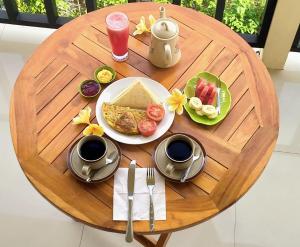 a wooden table with a plate of breakfast food on it at Mantra Guesthouse Sidemen in Sidemen